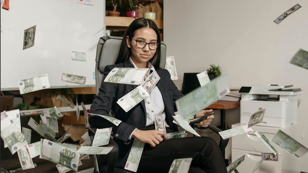 Woman sitting on a office chair, with cash raining all over