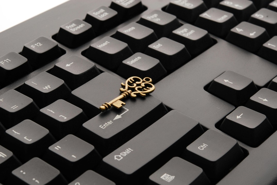 A small gold key on top of a black keyboard
